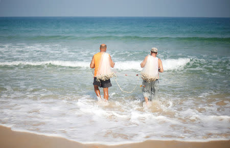 Palestinian fisherman Jihad al-Soltan (L) walks to throw his net in the sea in the northern Gaza Strip August 21, 2017. REUTERS/Mohammed Salem