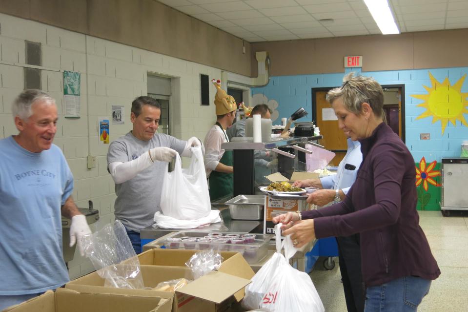 From left, volunteers Garry Clift and Joe Williams assemble to-go bags of Thanksgiving dinners at Adrian Public Schools' Drager Early Education Center for Cindy Beaubien, right, that she will give to guests or have delivered to homebound residents Nov. 28, 2019, during the 21st annual free Thanksgiving event hosted by the Kiwanis Club of Adrian, Alpha Koney Island and Adrian Public Schools.