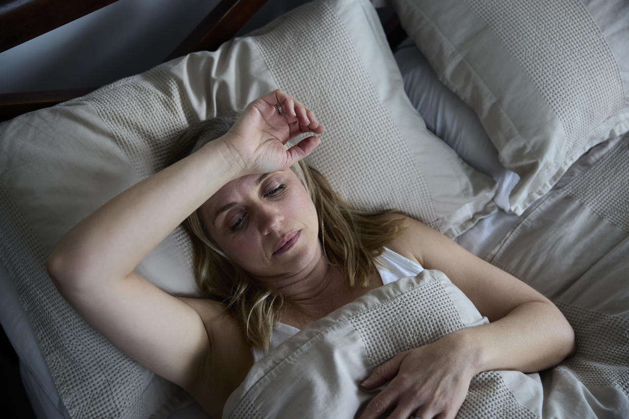 A woman lying in bed has trouble falling asleep.