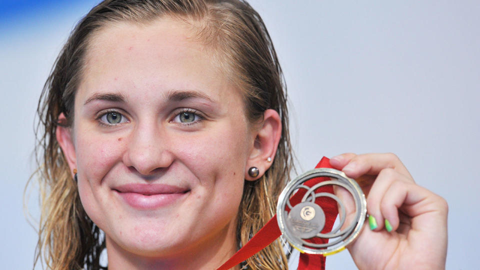 Pictured here, Maddie Groves holds one of her swimming medals aloft.