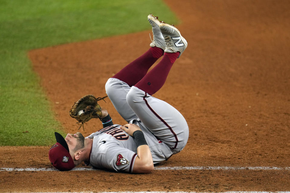 Arizona Diamondbacks first baseman Christian Walker falls backward after stretching to catch the throw for an out on a ground ball by Texas Rangers' Leody Taveras during the eighth inning in Game 2 of the baseball World Series Saturday, Oct. 28, 2023, in Arlington, Texas. (AP Photo/Julio Cortez)