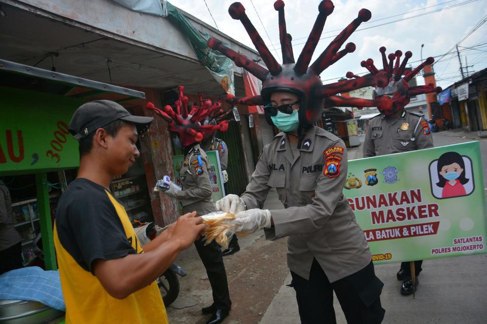 Police officers wearing helmets depicting coronavirus, distribute free masks amid the spread of the coronavirus in Mojokerto, East Java province, on April 8.