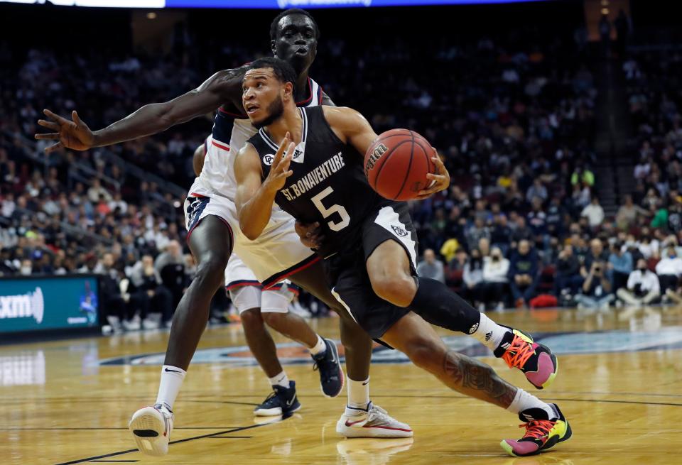 St. Bonaventure guard Jaren Holmes (5) drives to the basket against Connecticut forward Akok Akok (11) during the first half of an NCAA college basketball game in Newark, N.J., Saturday, Dec. 11, 2021. (AP Photo/Noah K. Murray)