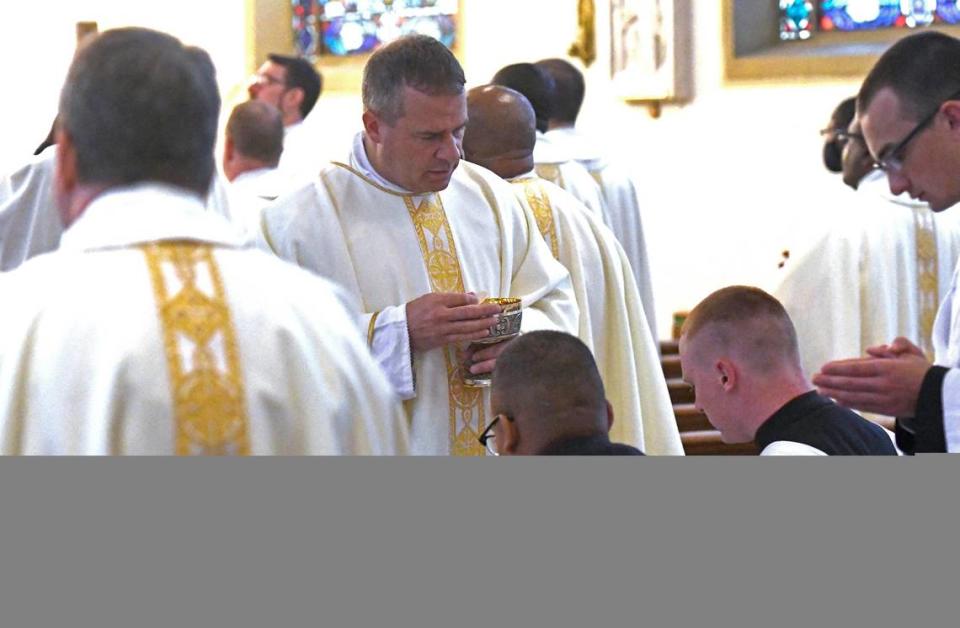 Fr. Matthew Kauth, rector of St. Joseph College Seminary, administers communion to young men discerning a vocation to the priesthood during Chrism Mass at St. Patrick Cathedral on Tuesday, March 30, 2021.