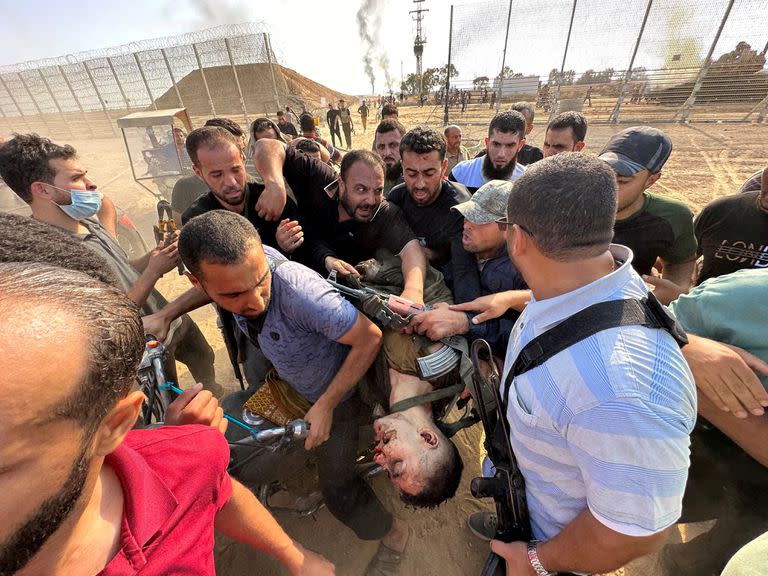 Palestinos llevan el cadáver de una persona que dicen que es un israelí asesinado por pistoleros de Hamas que se infiltraron en áreas del sur de Israel, en la frontera entre Israel y Gaza, el 7 de octubre de 2023