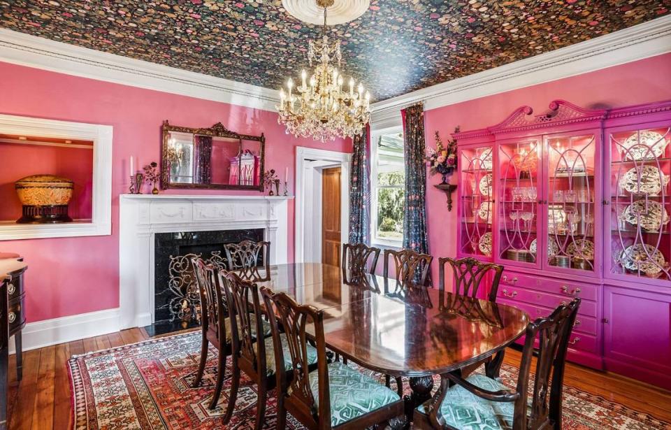 This dining room features pink walls and fruit wallpaper on the ceiling.