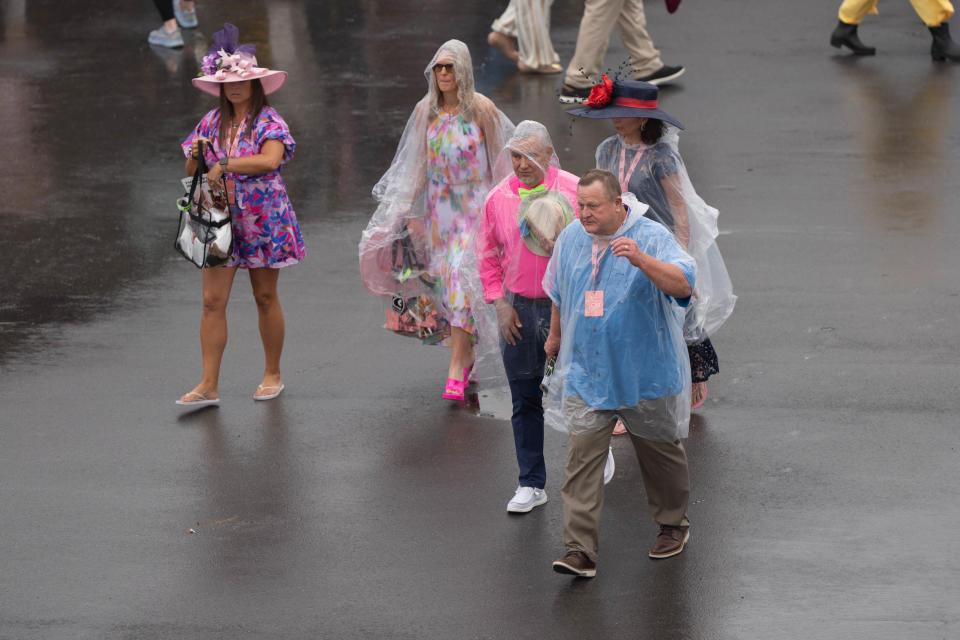 Attendees wear ponchos over their clothes to shield from the rain on Kentucky Oaks day at Churchill Downs on Friday, May 3, 2024.