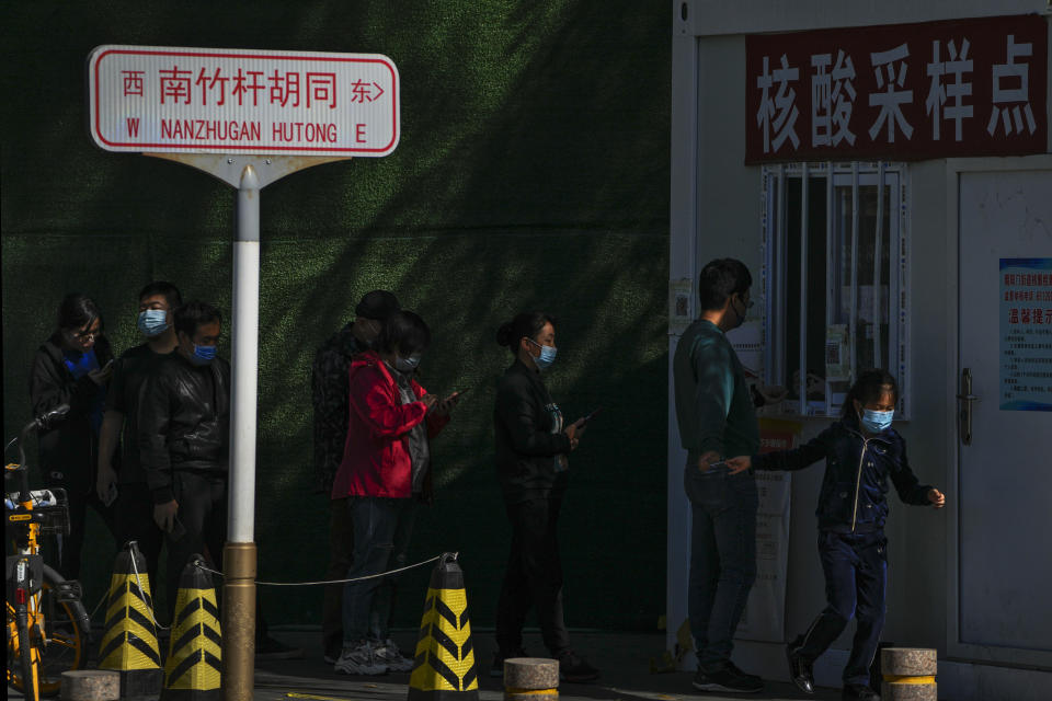 Residents wearing face masks line up to get their routine COVID-19 throat swabs at a coronavirus testing site setup along a pedestrian walkway in Beijing on Sunday, Oct. 16, 2022. The overarching theme emerging from China's ongoing Communist Party congress is one of continuity, not change. The weeklong meeting is expected to reappoint Xi Jinping as leader, reaffirm a commitment to his policies for the next five years and possibly elevate his status even further as one of the most powerful leaders in China's modern history. (AP Photo/Andy Wong)