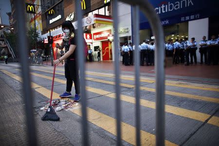 A pro-democracy protester sweeps a street after policemen removed some barricades, at a protest site at the commercial area of Causeway Bay in Hong Kong October 14, 2014. REUTERS/Carlos Barria