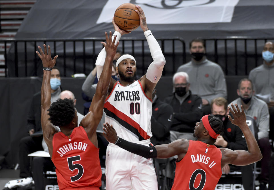 Portland Trail Blazers forward Carmelo Anthony, center, shoots over Toronto Raptors forward Stanley Johnson, left, and guard Terence Davis, right, during the second half of an NBA basketball game in Portland, Ore., Monday, Jan. 11, 2021. The Blazers won 112-111. (AP Photo/Steve Dykes)