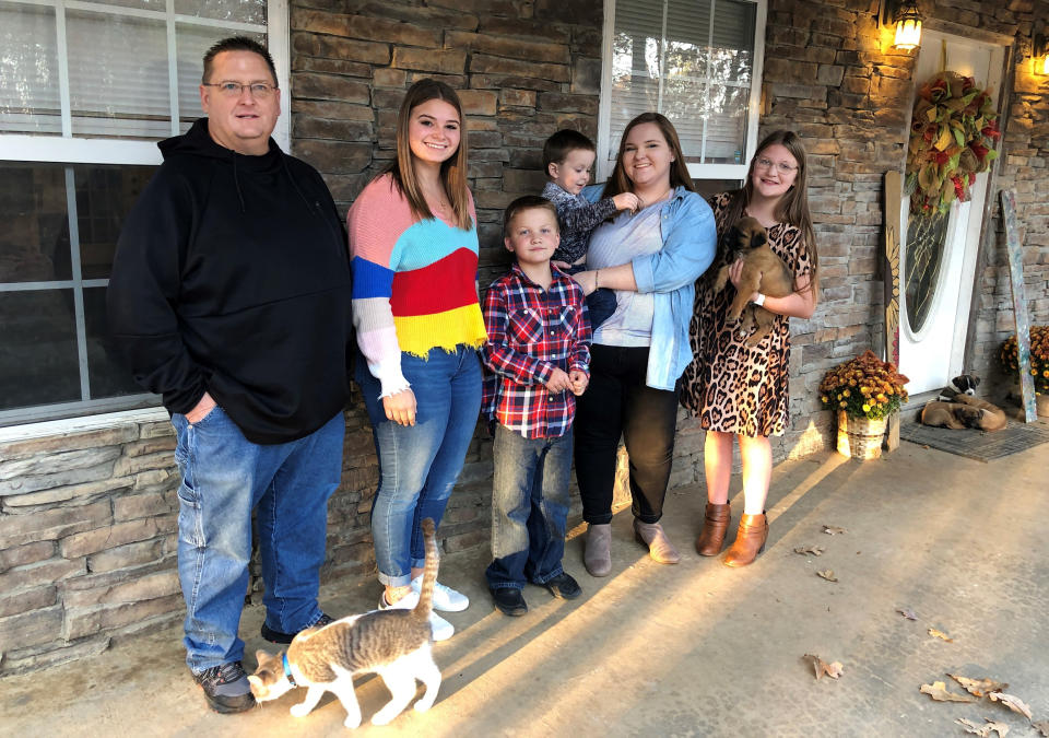 Keith Michael, left, poses with his children, from left, Jessica, Hunter, Houston, Sara and Holly, outside their home on Friday, Nov. 13, 2020, in Jonesboro, Ark. Among the victims of the coronavirus is Michael's wife, fourth-grade Arkansas teacher Susanne Michael, who died less than three months after celebrating the adoption of three of the children. (AP Photo/Adrian Sainz)