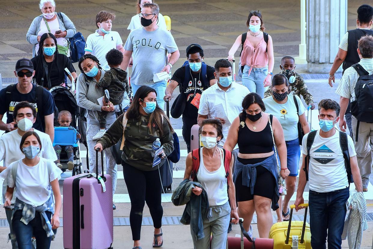 Travelers wearing protective face masks arrive at Orlando International Airport on the Friday before Memorial Day