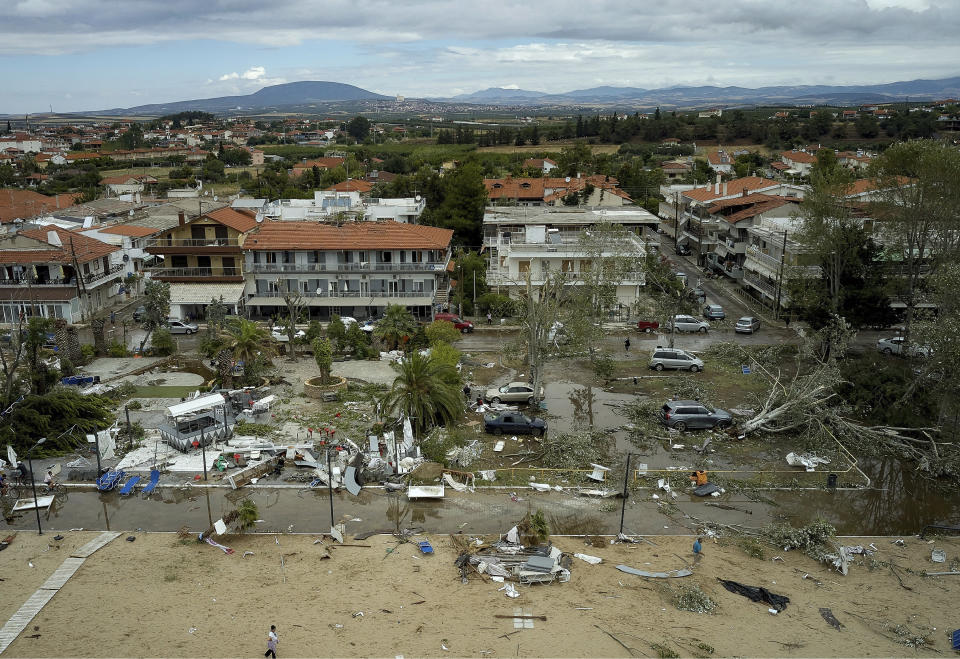 People search and clean a damaged square after a storm at Sozopoli village in Halkidiki region, northern Greece, Thursday, July 11, 2019. A search and rescue operation is underway in northern Greece for a fisherman missing after a powerful storm left six people dead, including two children, and injured more than 100. (Vassilis Konstantopoulos/InTime News via AP)