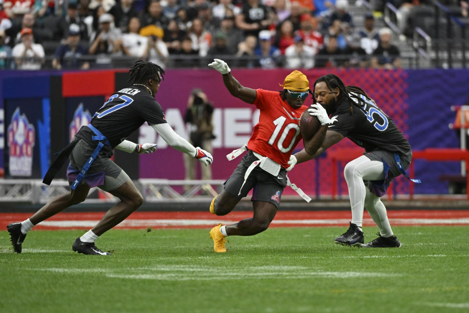 FILE - AFC wide receiver Tyreek Hill (10) of the Miami Dolphins carries the ball against NFC cornerback Tariq Woolen (27) of the Seattle Seahawks and outside linebacker Za'Darius Smith (55) of the Minnesota Vikings during the flag football event at the NFL Pro Bowl, Sunday, Feb. 5, 2023, in Las Vegas. The folks who allowed 3-on-3 basketball — also known as pick-up games at the local Y — into their grandiose spectacle and went along with the idea of handing out gold medals next summer for breakdancing are trying to lock down which new sports make the cut for the 2028 Los Angeles Games. Nine are under consideration, but the one that caught my eye was the flagged, non-contact version of the game that dominates the American sporting landscape but is barely a blip to the rest of the world. (AP Photo/David Becker, File)