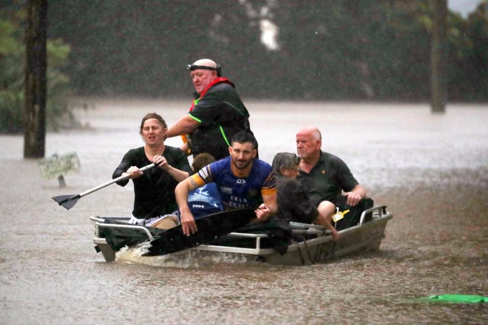 People use a small boat to travel through flood water in Lismore (AP)