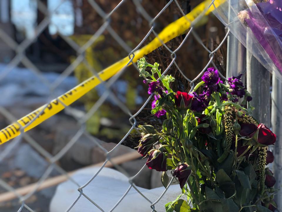 In this February photo, a bouquet of flowers rests against the fence encircling a southwest Fort Collins home where a body was found after a Feb. 7 house fire.