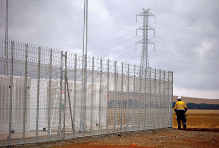 A worker walks along the fence for the compound housing the Hornsdale Power Reserve, featuring the world's largest lithium ion battery made by Tesla, during the official launch near the South Australian town of Jamestown, in Australia, December 1, 2017. REUTERS/David Gray