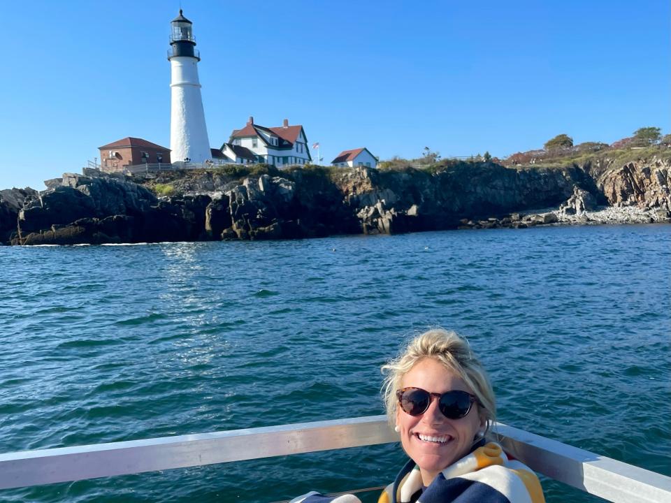 The writer wrapped in a towel on boat in water beside lighthouse