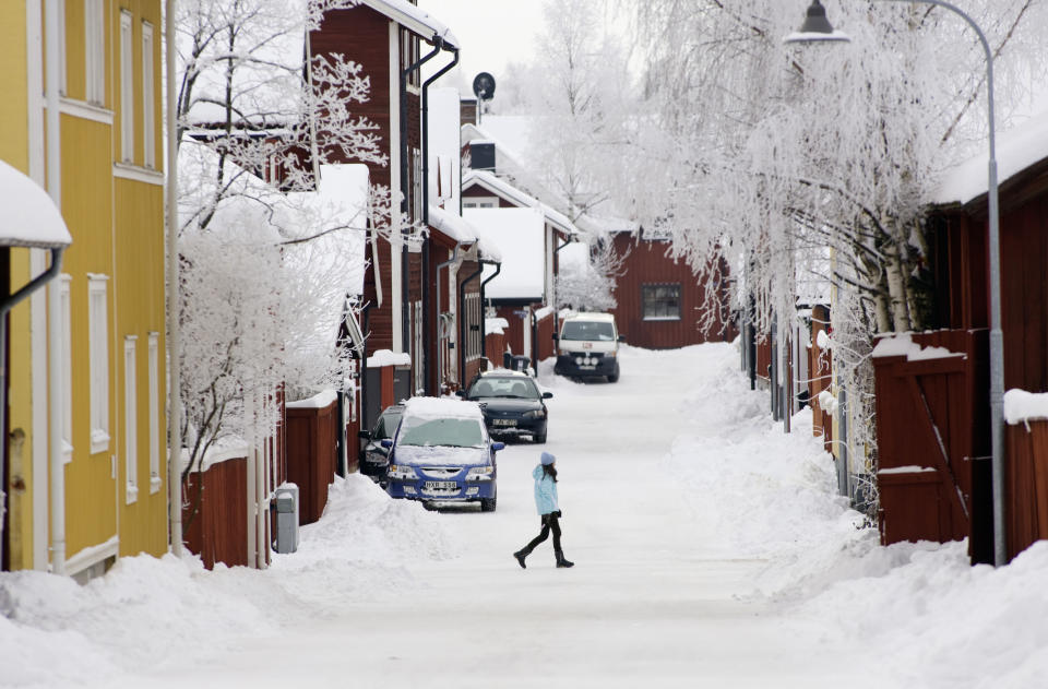 A woman walking in the middle of a snowy street.