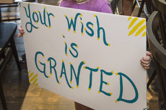 FILE - In this photo from 2019, a girl holds a sign while waiting for her cousin to arrive for a surprise Make-A-Wish announcement in Rogers, Arkansas.