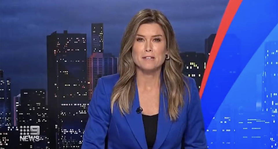 9 News reader Amber Sherlock sits behind the news desk wearing a blue blazer.