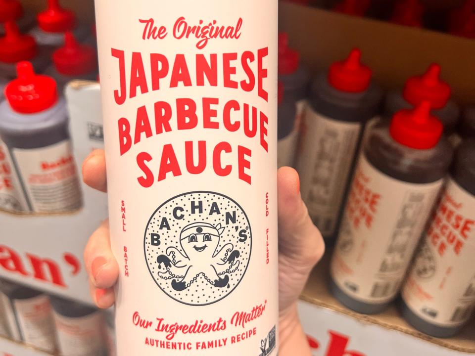 hand holding up a big bottle of bachan's Japanese barbecue sauce at costco