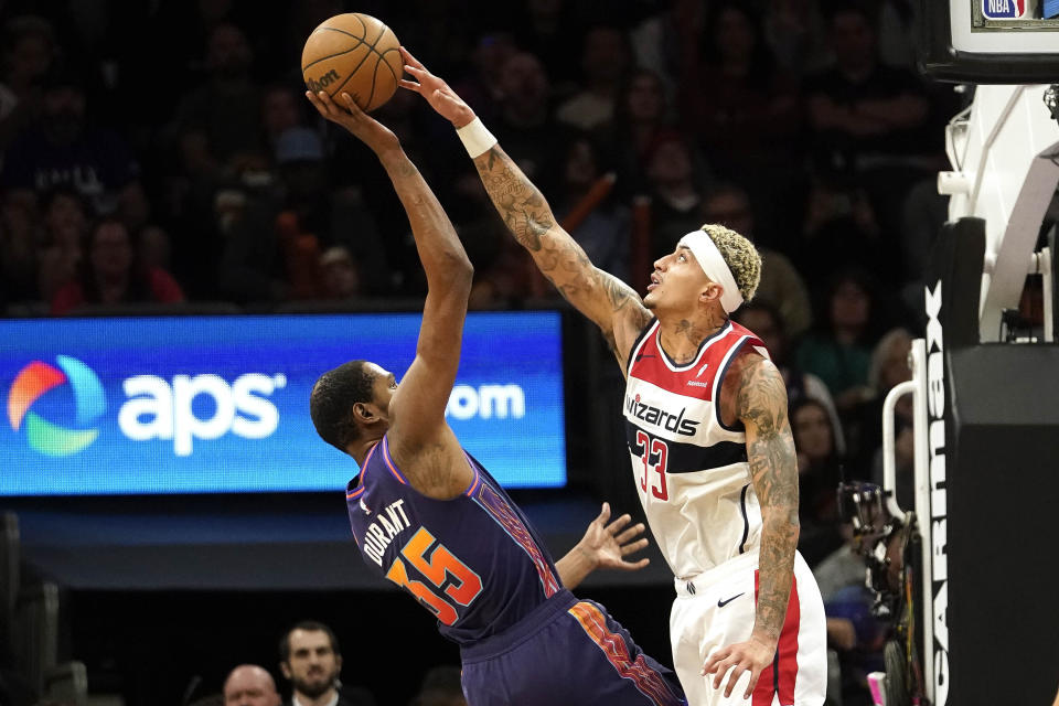 Washington Wizards' Kyle Kuzma (33) gets to the ball as Phoenix Suns' Kevin Durant (35) shoots during the second half of an NBA basketball game in Phoenix, Sunday, Dec. 17, 2023. (AP Photo/Darryl Webb)