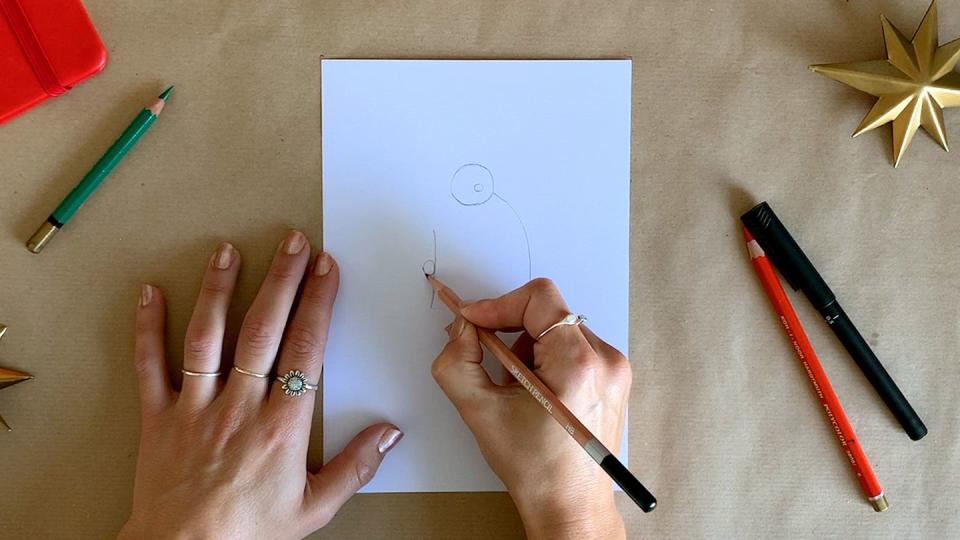 a person drawing santa's hand with a pencil on white paper