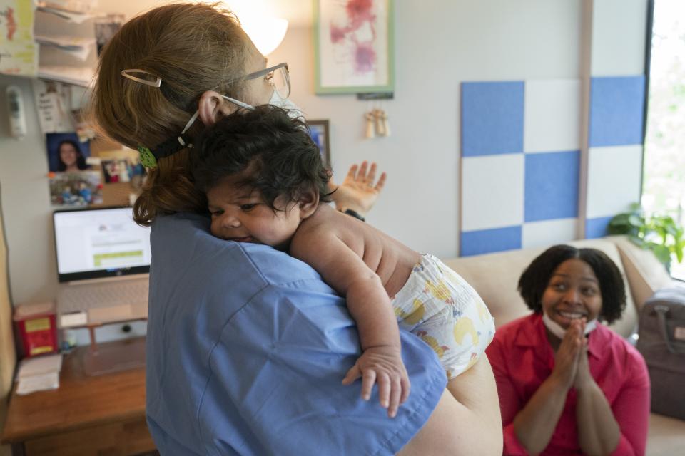 Capri Isidoro, of Ellicott City, Md., right, claps on hearing reassuring advice from Ann Faust, an International Board Certified Lactation Consultant (IBCLC), holding Isidoro's one-month-old baby Charlotte, Monday, May 23, 2022, in Columbia, Md., during a lactation consult at Baby and Me Lactation Services. Baby Charlotte was delivered via emergency c-section and given formula by hospital staff. Isidoro has been having trouble with breastfeeding and has been searching for a formula that her daughter can tolerate well. "If all things were equal I would feed her with formula and breastmilk," says Isidoro, "but the formula shortage is so scary. I worry I won't be able to feed my child." (AP Photo/Jacquelyn Martin)