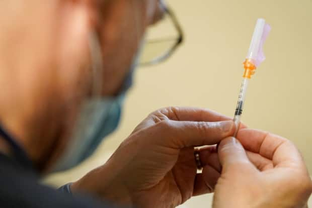 A health worker prepares a vaccine dose at a mobile vaccine clinic in Ottawa on Friday. Newfoundland and Labrador is reporting three new cases of COVID-19 and three new recoveries on Monday. (Francis Ferland/CBC - image credit)