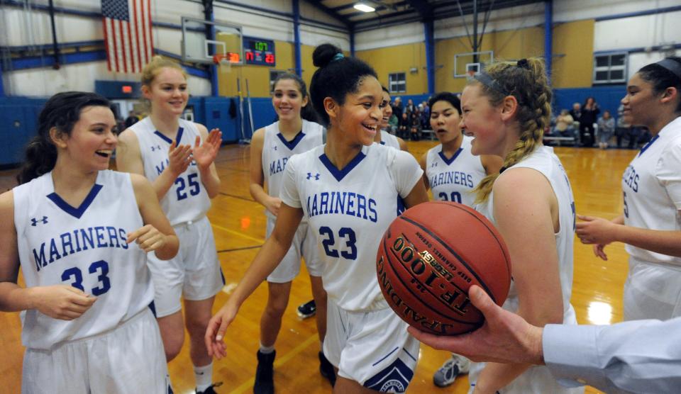 Kendall Currence (23) receives the game ball as she celebrates with her Falmouth Academy team after passing 2,000 points during their game with Barnstable Jan. 24, 2017.