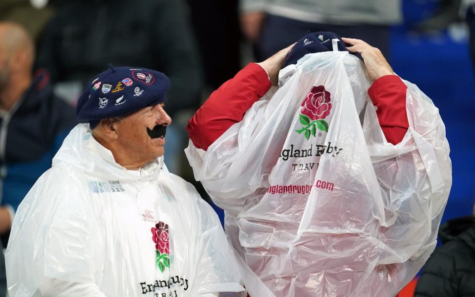 England fans in the stands don water-proof ponchos and (left) a distinctly French beret