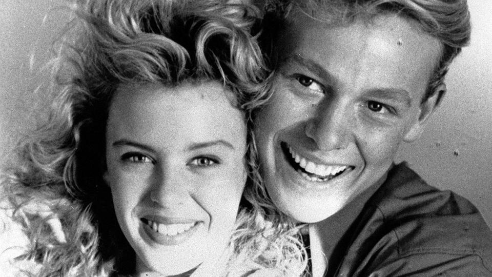 A black-and-white photo of Jason Donovan hugging Kylie Minogue
