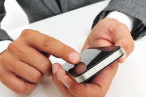 a businessman sitting in a table using a smartphone