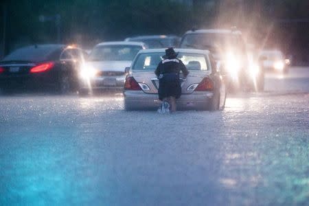 A man pushes a stranded car through a heavily flooded road in downtown Houston, Texas May 30, 2015. REUTERS/Lee Celano