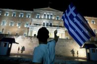 A man holds a Greek national flag as he celebrates in front of the parliament on July 5, 2015 in Athens after results showed those who rejected further austerity measures in a crucial bailout referendum had won