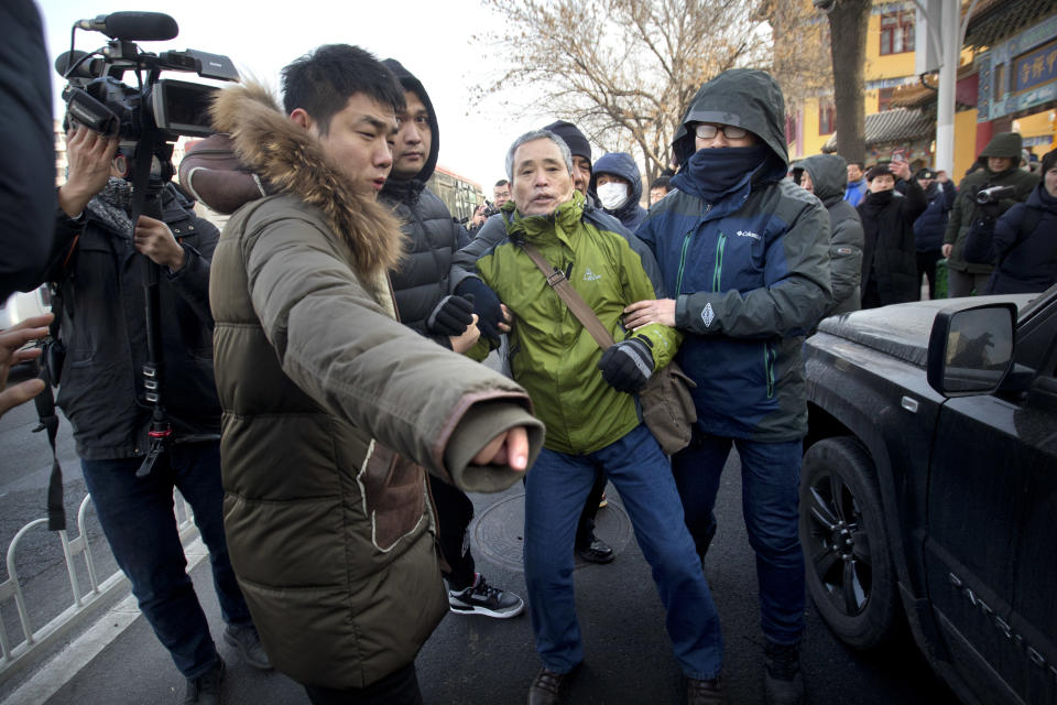 Plainclothes security officers take away a supporter of Chinese human rights lawyer Wang Quanzhang near the Secondary Intermediate People's Court of Tianjin northeastern China's Tianjin municipality, Wednesday, Dec. 26, 2018. The trial of Wang, who was charged with subversion of state power in 2016, was expected to begin at the court on Wednesday morning. (AP Photo/Mark Schiefelbein)