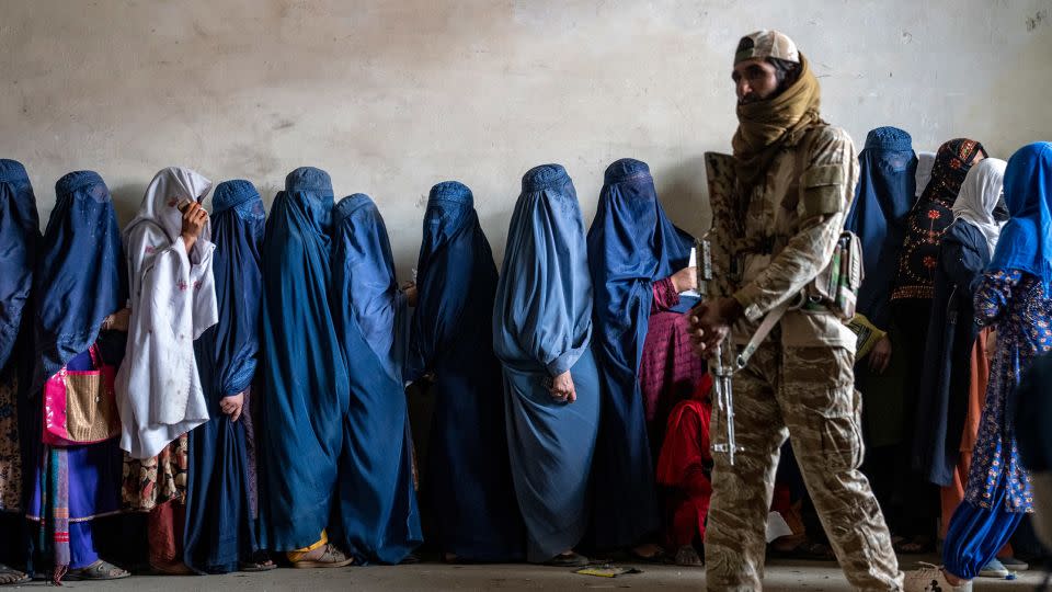 A Taliban fighter stands guard as women wait to receive food rations distributed by a humanitarian aid group, in Kabul, Afghanistan, on May 23, 2023. - Ebrahim Noroozi/AP/File