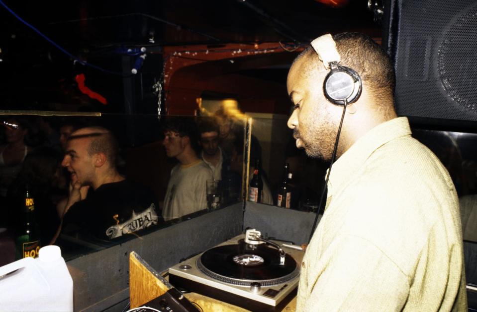 A man wearing headphones stands by a record player