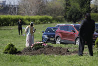 Parientes y amigos acompañan a distancia o desde sus vehículos a Erika Bermudez, que permanece al lado de la tumba de su madre Eudiana Smith, fallecida de COVID-19, el sábado 2 de mayo de 2020, en el cementerio Bayview, en Jersey City, Nueva Jersey. Se permitió a Bermudez acercarse al lugar hasta después de que Smith fue totalmente inhumada. Amigos y parientes tuvieron que permanecer en sus vehículos. (AP Foto/Seth Wenig)