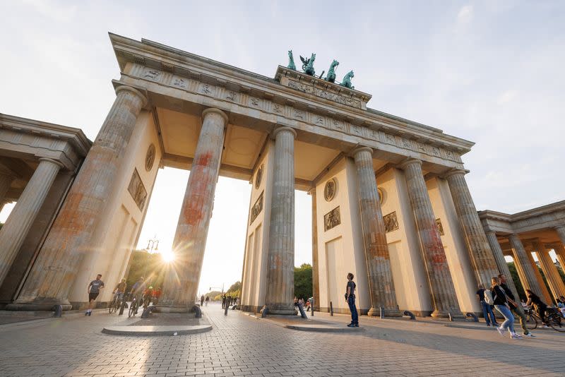 The sun sets behind Brandenburg Gate and its columns that were painted in a protest campaign by Last Generation climate activists in Berlin