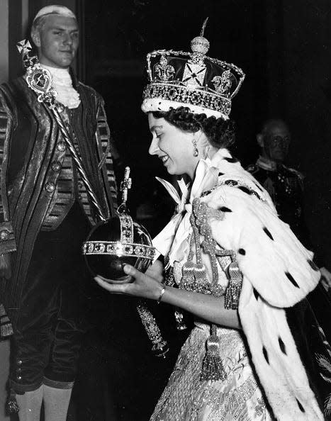 The queen wearing the St Edward's Crown, holding the orb and sceptres.