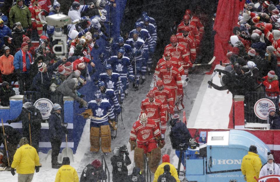 The Detroit Red Wings, right, and the Toronto Maple Leafs walk out to the rink as a light snow falls at Michigan Stadium for the start of the Winter Classic outdoor NHL hockey game in Ann Arbor, Mich., Wednesday, Jan. 1, 2014. (AP Photo/Carlos Osorio)