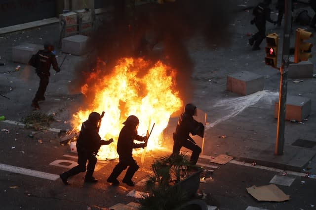 Police officers run past a burning barricade on the fifth day of protests 