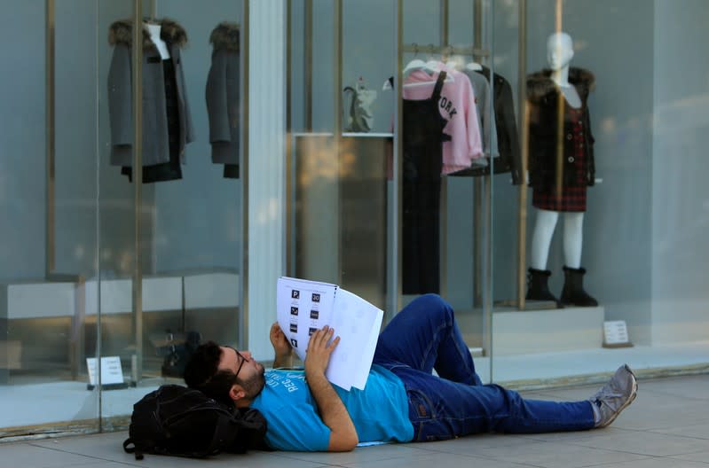 A demonstrator reads a book as he lies on the ground during ongoing anti-government protests, in the southern city of Sidon