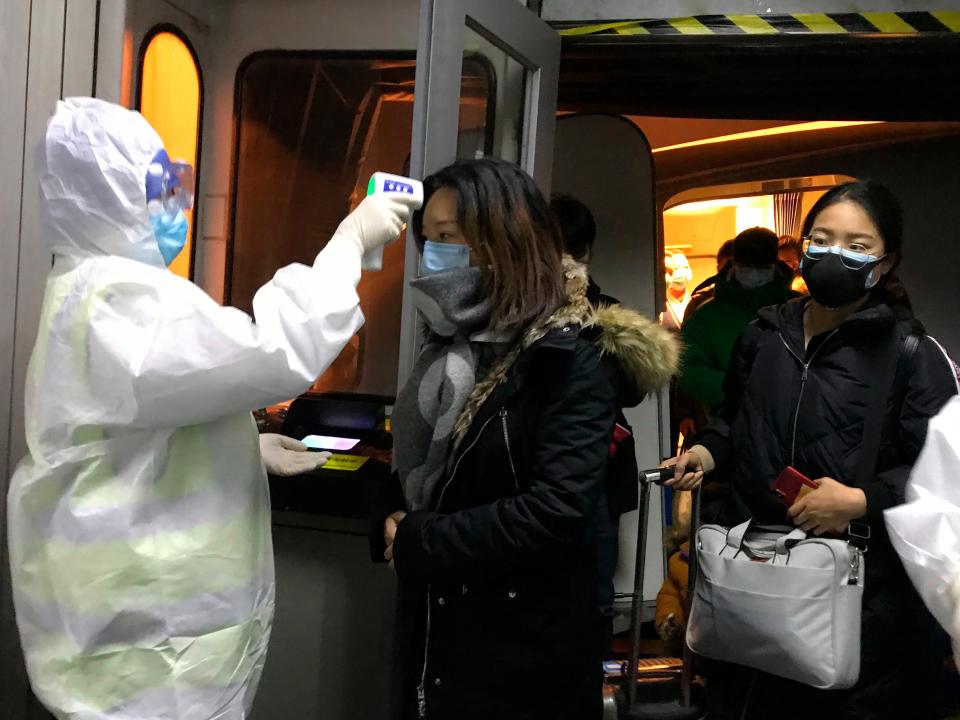 Health Officials in hazmat suits check body temperatures of passengers arriving from the city of Wuhan Wednesday, Jan. 22, 2020, at the airport in Beijing, China. Nearly two decades after the disastrously-handled SARS epidemic, China’s more-open response to a new virus signals its growing confidence and a greater awareness of the pitfalls of censorship, even while the government is as authoritarian as ever. (AP Photo Emily Wang)