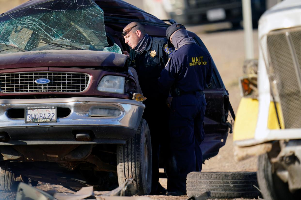 Law enforcement officers sort evidence and debris at the scene of a deadly crash in Holtville, Calif. on Tuesday, March 2, 2021. Authorities say a semi-truck crashed into an SUV carrying 25 people on a Southern California highway, killing at least 13 people.