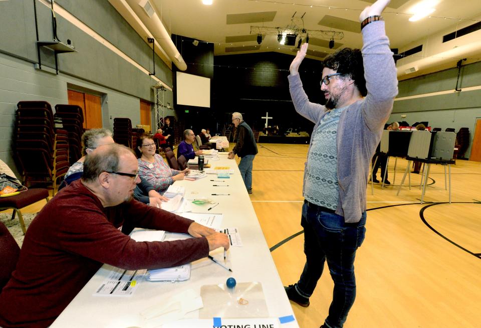 Nathan Armbruster, right, throws his hands up in celebration after being told by election judge Brian Deslue that he is the 100th voter in Precinct 22 at Lakeside Christian Church in Springfield on Tuesday.