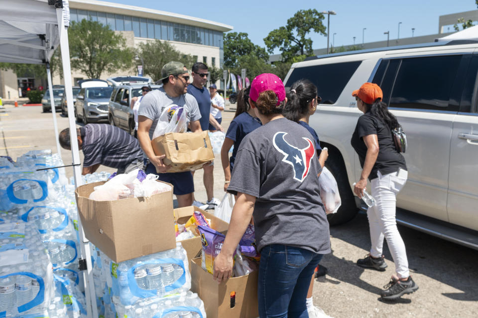 Volunteers prepare boxes of dry foods and fresh fruit to distribute as cars wrap around Houston Community College Eastside Campus Sunday, May 19, 2024, in Houston, Texas. People picked up dry foods, water, ice, milk and baby supplies following severe storms that passed through the area earlier in the week. (Kirk Sides/Houston Chronicle via AP)