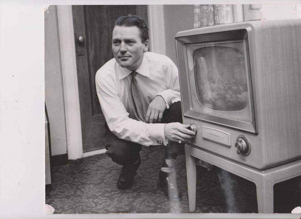 Charles McGraw adjusts the TV set in his Des Moines hotel room  Feb. 7, 1955.